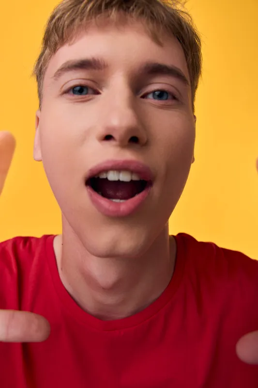 Closeup of a joyful male shouting into the camera, energetic expression and vibrant colors create a dynamic selfie scene perfect for social media, promotion, or announcement