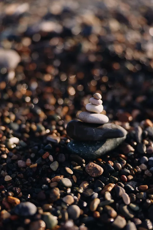 Stacked stones form a quiet balance on a pebble beach with soft light, a zen inspired meditation scene, natural harmony and calm focus captured in texture and shoreline stillness