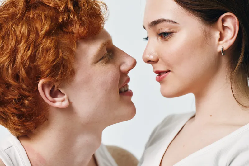 Couple, man and woman looking at each other with affection, intimacy and love on white background. Young people closeup portrait with smiling faces and gentle expressions for relationship.