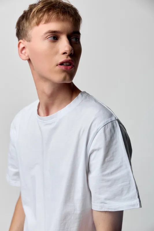 Youngman model whitetshirt sideprofile casual apparel photography studio minimalism clean neutral lighting fashion male everydaywear contemporary calm pose studioshoot simple effortless modern