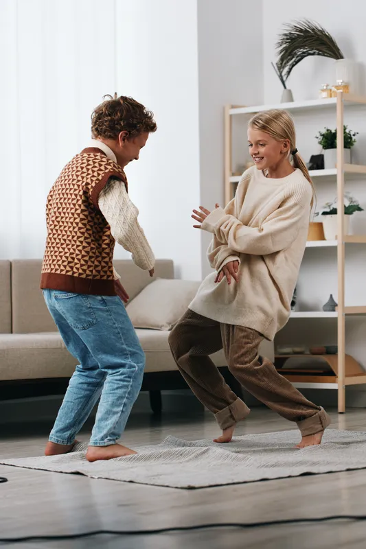 Authentic scene of two children dancing at home, capturing playful energy and a school inspired lifestyle moment that highlights joy, movement, and everyday learning.