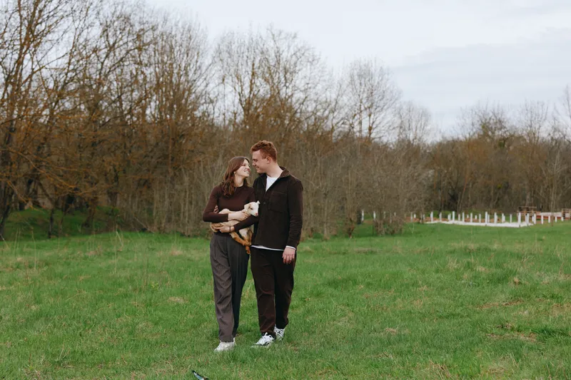 Candid scene of a couple walking in a green field, embracing and sharing a warm moment under cloudy skies, showcasing lifestyle, affection, and connection in a relaxed outdoor setting calm