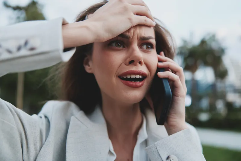 stressed woman talking on phone showing anxiety and frustration in casual business clothing outdoors KEYWORDS: stressed woman, woman, anxiety, frustration, business, phone call, casual, emotion, upset