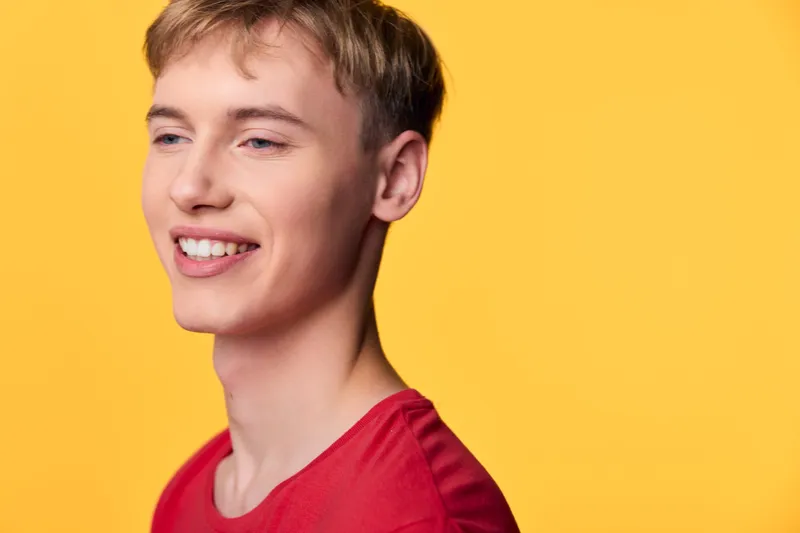Smiling man in a red shirt against a bright yellow background, showcasing warmth and approachability for lifestyle, close up, positive mood, vibrant colors, friendly energy