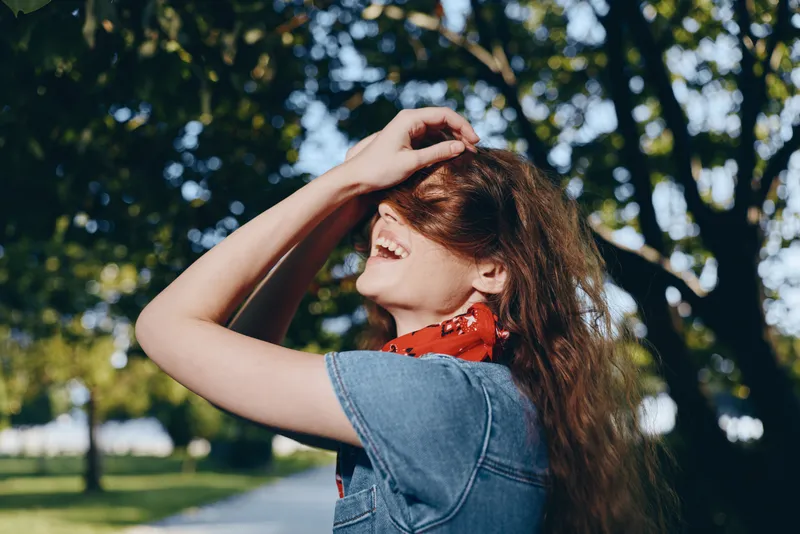 lifestyle woman in modern boho-western denim street style smiling outdoors with natural sunlight and vibrant film color tones on a warm day