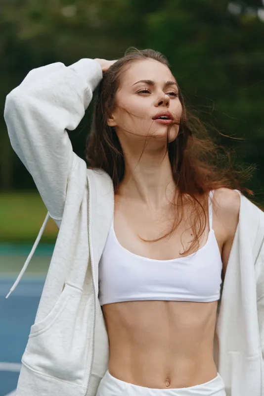 Young woman in sportswear enjoying an outdoor workout, showing confidence and joy, with a vibrant green background in a summer setting