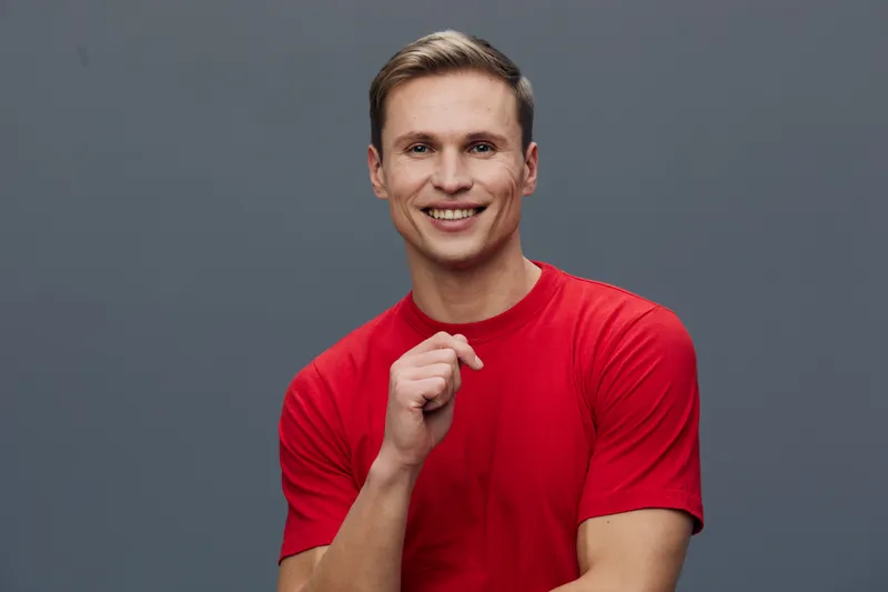 smiling young caucasian man wear red t-shirt isolated gray background happy cheerful positive emotions digital nomad concept