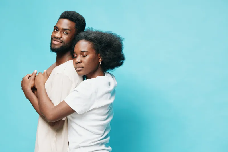 Couple embracing with closed eyes, showcasing love and connection against a vibrant blue background, perfect for relationship or emotional themes