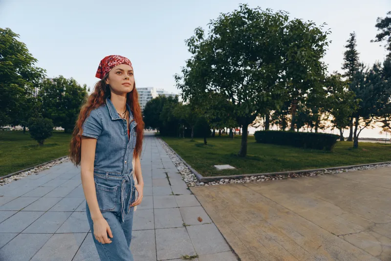 Lifestyle woman in modern boho-western denim street style walking confidently outdoors with film color tones and casual urban background during daytime.