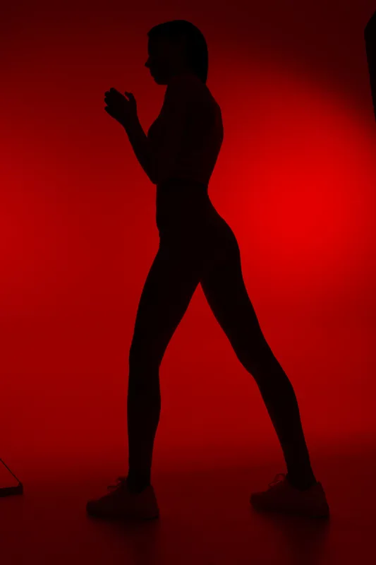 silhouette of woman sport fitness in dynamic pose with vibrant red background, showcasing strength, athleticism, and motion in studio lighting
