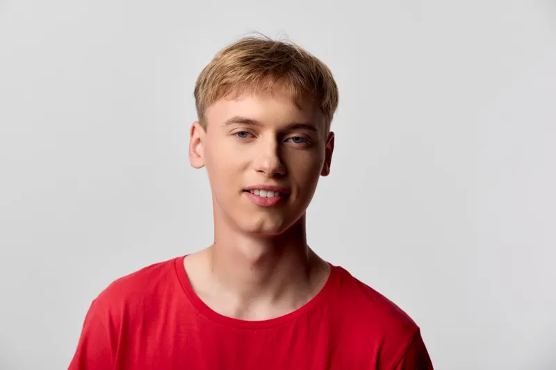 Young man, smile, red shirt, studio setting, casual style, male model in a clean backdrop, suitable for lifestyle, fashion and marketing visuals with natural expression and approachable vibe
