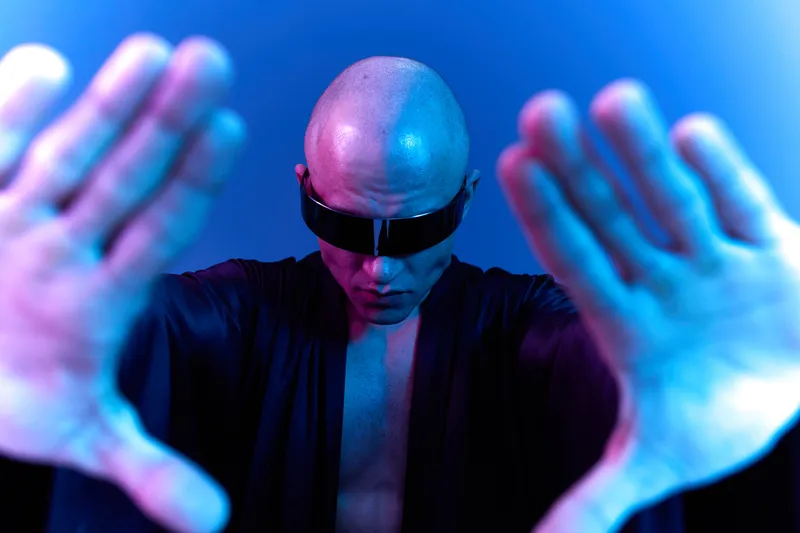 A striking image of a bald man in sunglasses, creating a captivating visual effect with extended hands. The colors blend in a mesmerizing way, emphasizing a unique atmosphere.