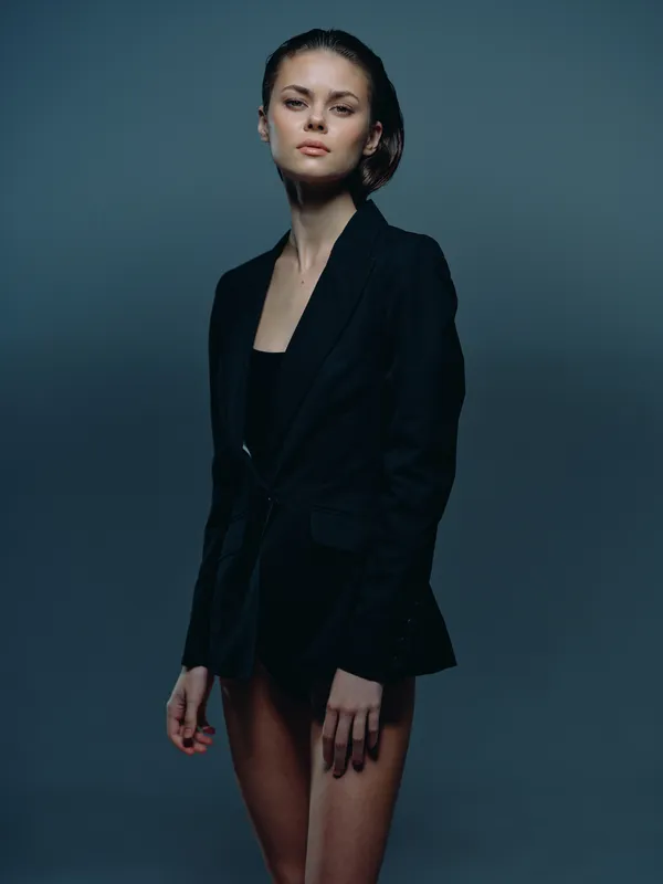 confident woman wearing black blazer with serious expression in dark studio lighting