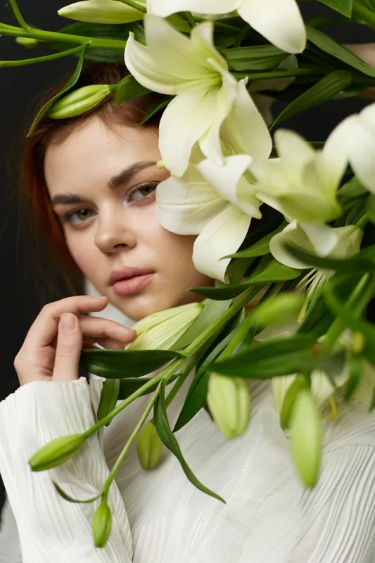 A serene portrait of a young woman surrounded by white lilies, showcasing natural beauty and calm emotions in a delicate, spring inspired scene