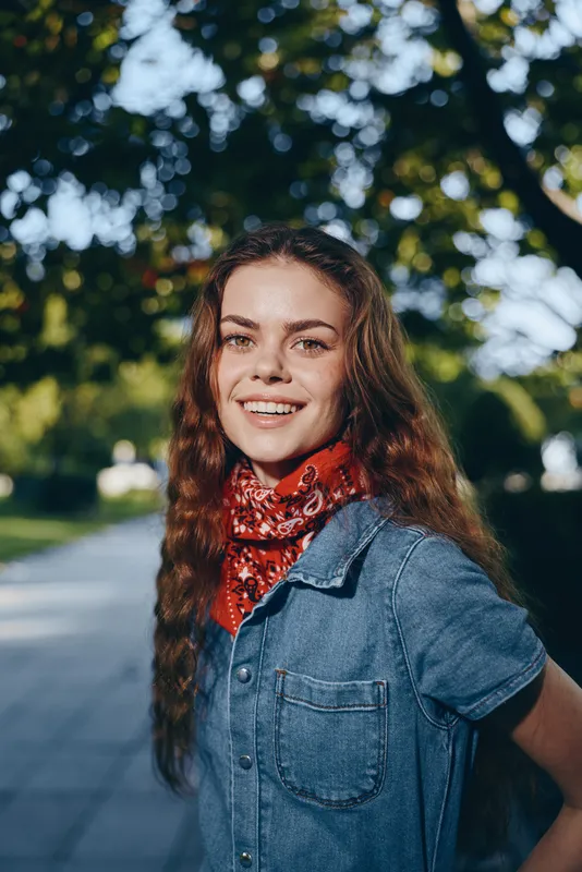 lifestyle woman in modern boho-western denim street style wearing a red bandana, smiling outdoors in natural light with film color effect, casual and trendy look
