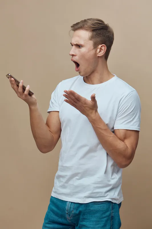 surprised man using mobile phone hold hand casual wear white t-shirt communicating chatting with AI voice assistant beige background digital technology concept