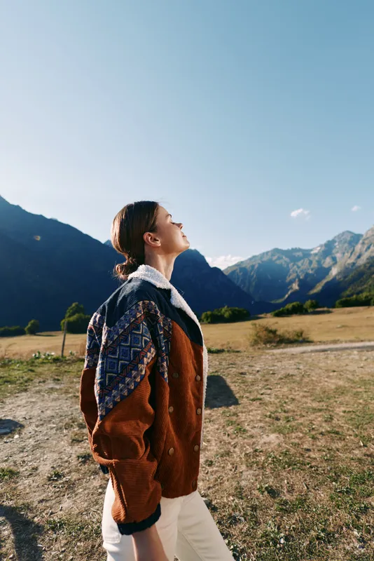 Woman profile hiking in mountains with backpack, nature travel and outdoors scene. Young adult portrait walking in a valley under clear blue sky, scenic landscape with sunlight and freedom.