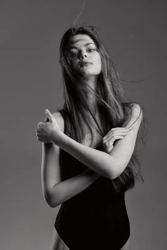 Black and white portrait of a young woman with long hair in a leotard expressing calm and grace.