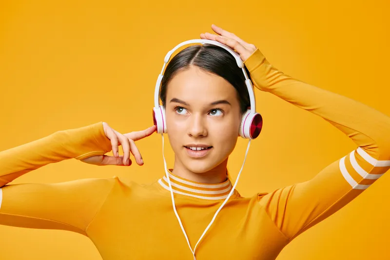 Woman in orange athletic top wearing headphones, ready for fitness workout in vibrant studio, showcasing sport focus, energy, balance and motivation for active lifestyle.