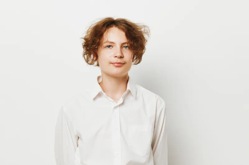 Professional young man stands against a solid colored background, exuding calm confidence in a clean, isolated studio setting that emphasizes a business vibe.