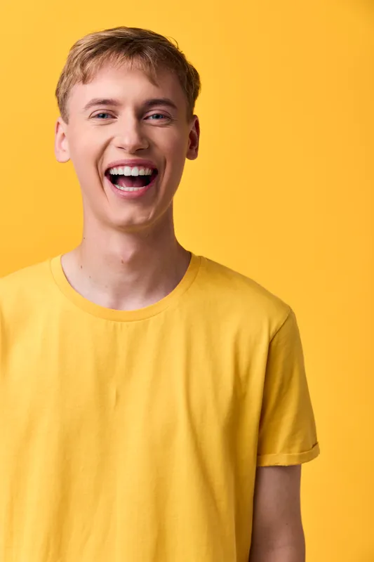 Smiling male in a bright yellow t shirt against a solid yellow backdrop, conveying energetic happiness, casual fashion and cheerful mood for lifestyle stock