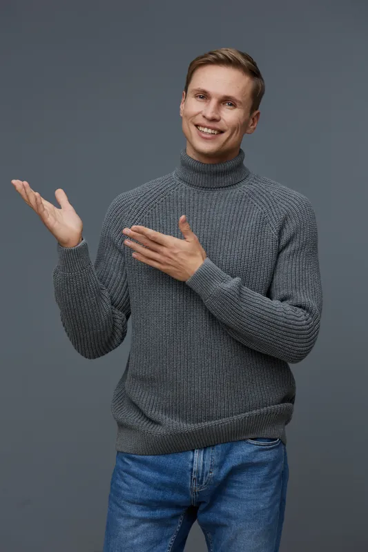 smiling young caucasian man wear gray turtleneck present gesture look camera isolated on gray background studio portrait digital nomad concept