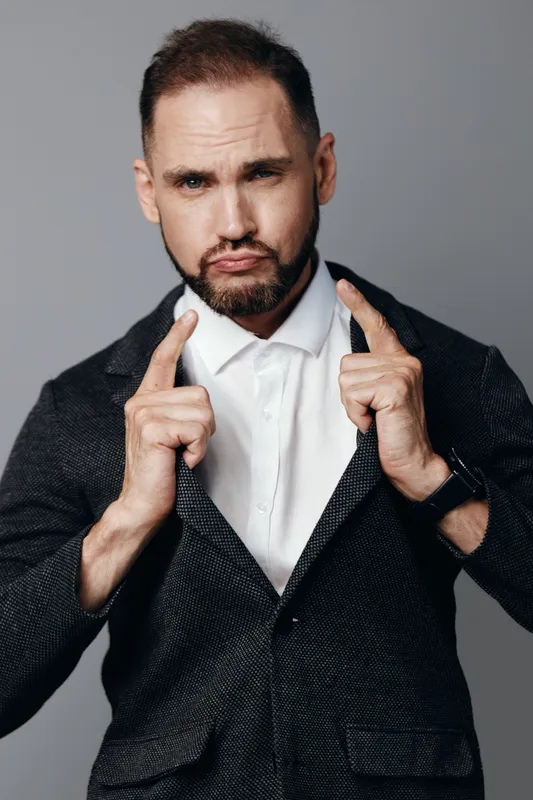 A professional man in a suit stands against a solid colored background, exuding confidence and focus with a determined gaze.