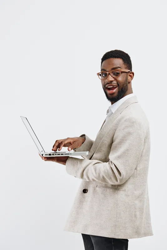 Confident smiling man with glasses hold laptop computer in hand looking at camera in studio white background. Business casual style. Person people concept