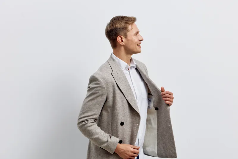 smiling man wearing checkered jacket shirt standing sideview looking away isolated on plain light background digital nomad remote work concept