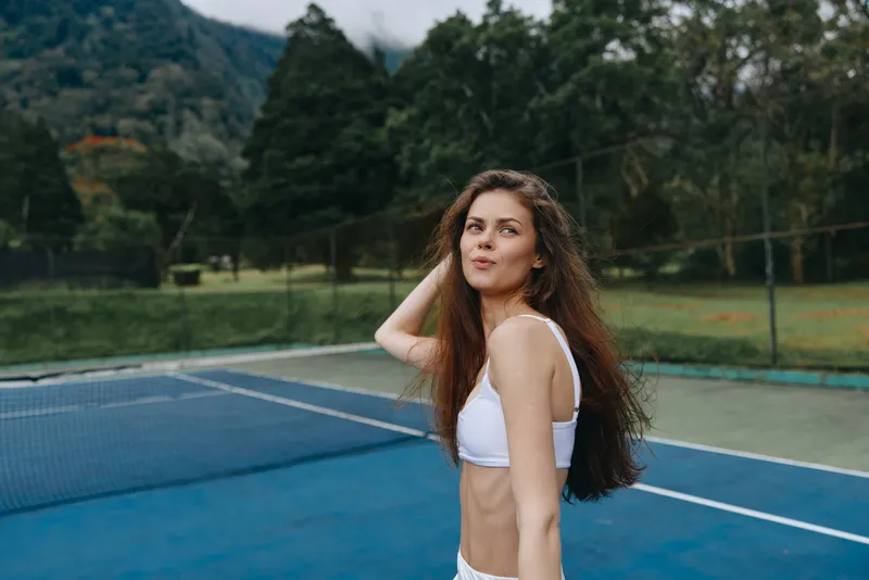 Outdoor tennis player in stylish sportswear showing confidence, enjoying a sunny day on the court, highlighting athleticism and healthy lifestyle