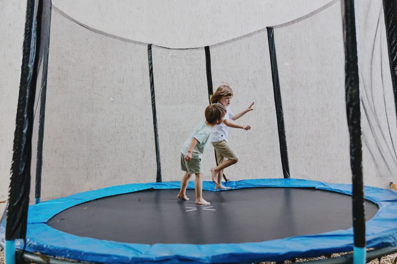 Happy children playing on a trampoline, enjoying active outdoor fun in a safe environment, showcasing laughter and excitement during summer days.