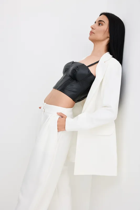 stylish woman in white pants and black corset leaning back against white background, modern fashion look with casual elegance and minimalistic style