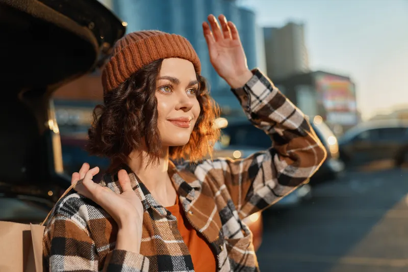 woman portrait beanie smile city car candid golden hour glow authenticity and mindful living in an urban scene, emotional storytelling captured with warm sunset light and relaxed mood.