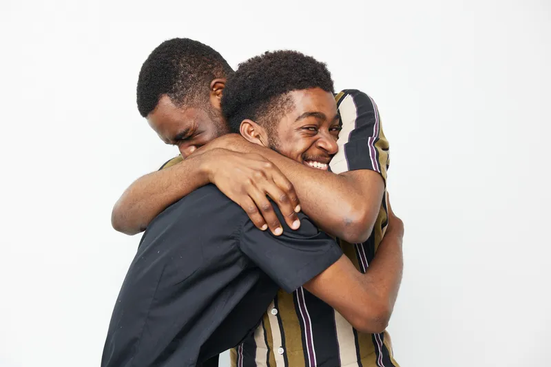 Two joyful black men embracing each other, showcasing friendship, happiness, and connection. This vibrant moment captures the essence of positivity and love.