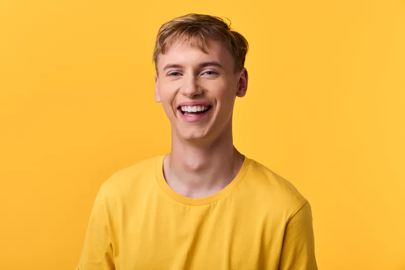 Smiling man in a yellow shirt against a bright yellow backdrop, conveying positivity, energy, and an approachable vibe suitable for lifestyle, marketing, or wellness campaigns