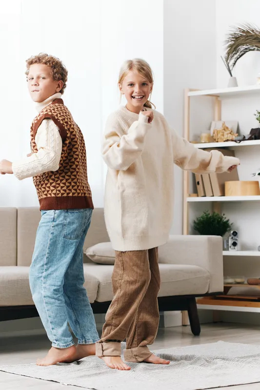 Authenticity and playful vibe define this scene of kids at home, a school themed lifestyle moment showcasing imaginative play, relaxed fashion, and confident movement in a cozy living space.