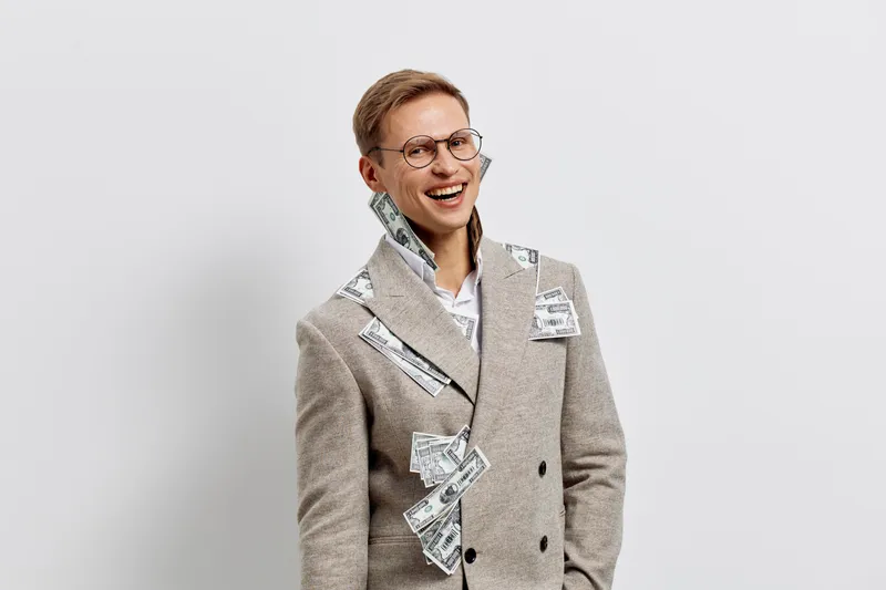 smiling man with money cash banknotes in pockets wear stylish gray coat glasses isolated on white background digital nomad concept