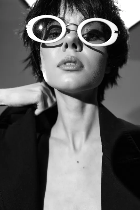 Stylish woman wearing oversized round sunglasses in black and white portrait with confident expression