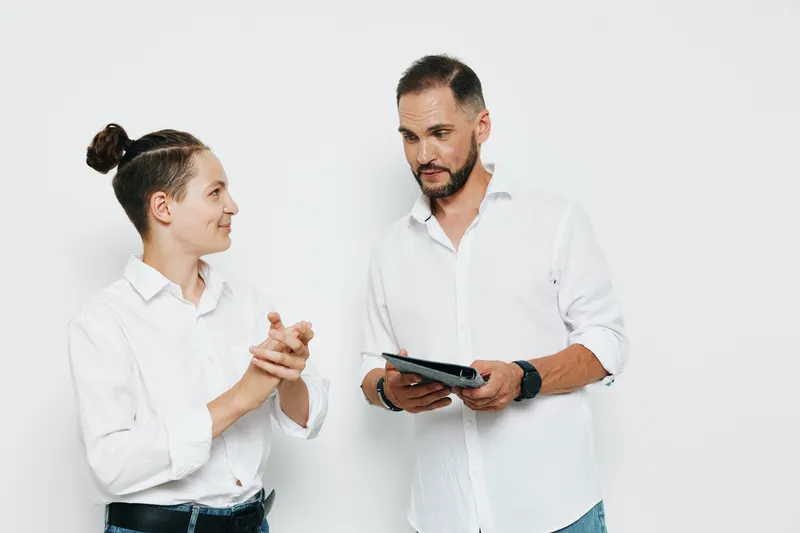 A professional man and colleague share a focused moment in front of an isolated colorful backdrop, showcasing confidence, collaboration, and positive business emotions.