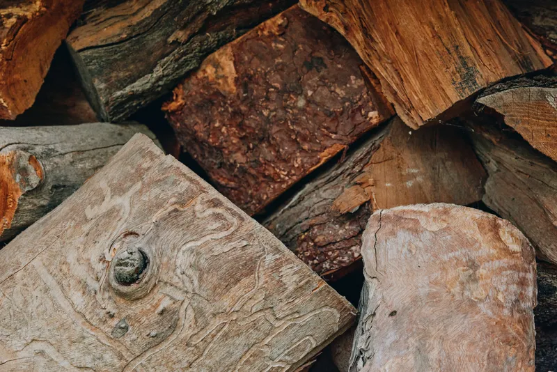 Firewood, logs, woodpile, timber, split logs, stacked wood: closeup of seasoned firewood pile with rough bark and grain, rustic outdoor cabin supply for middle-aged couple preparing cozy autumn