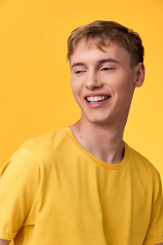 smile, man in a bright yellow shirt stands in a warm studio, radiating joyful energy and sunny style for lifestyle and fashion stock photography