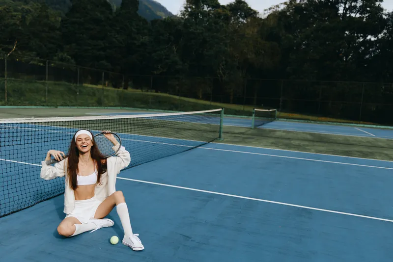 Cheerful young woman playing tennis on the court, embodying sports spirit with bright clothing, showcasing happiness and energy on a sunny day