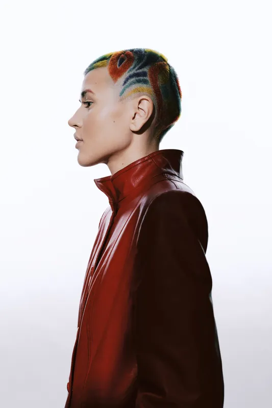 woman with colorful short hair wearing red leather jacket, side profile portrait with white background, unique hairstyle, modern fashion look