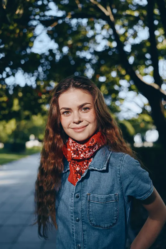 lifestyle woman in modern boho-western denim street style wearing a red bandana smiling outdoors in natural light with film color effect
