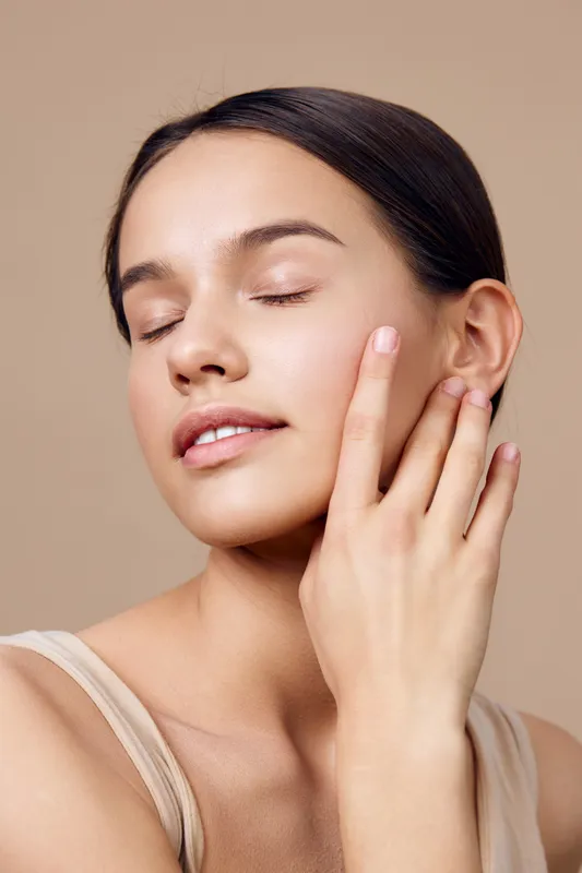 Elegant young woman with closed eyes, showcasing natural beauty and radiant skin in a neutral background, representing self care, skincare routine, and serenity