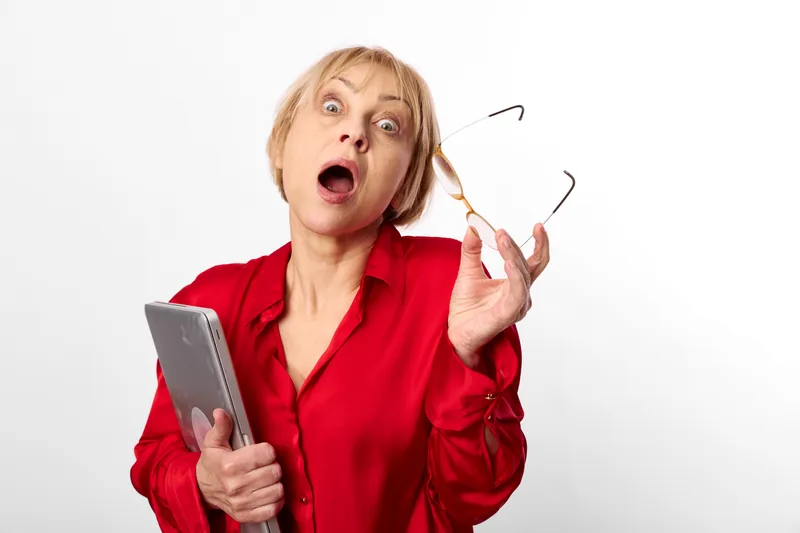 Woman holding a tablet, surprised shock expression, red blouse portrait, studio white background, technology communication, digital media, alert, soft light