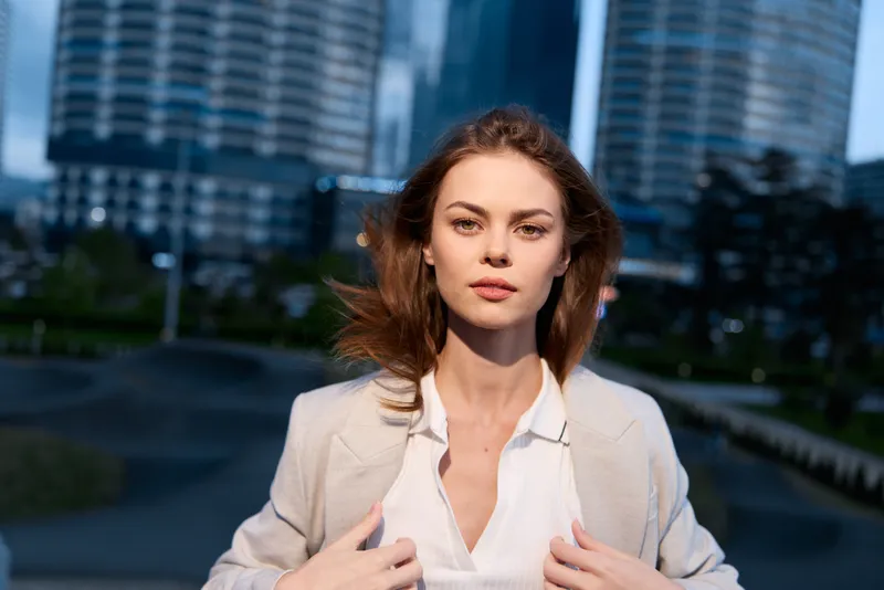 confident woman in business attire standing outdoors in modern cityscape with serious expression