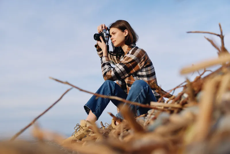 photography, photographer, outdoor, nature, camera, lens, sitting, woman, exploring, scenery, autumn, wind, daylight, focus. A thoughtful photographer studies the view with camera raised as waves