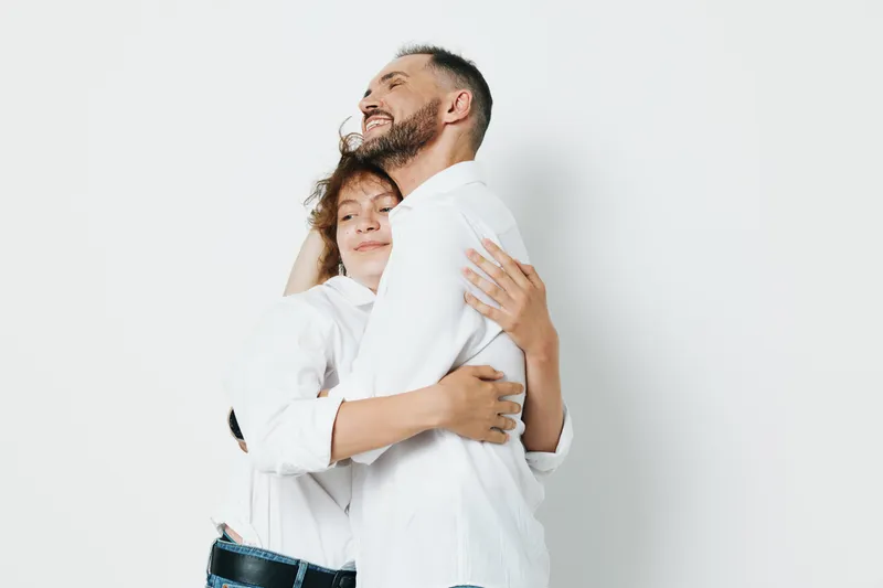 Professional man in business attire shares a warm hug, expressing trust, leadership, and success emotions, portrayed against an isolated soft color backdrop to convey focus.