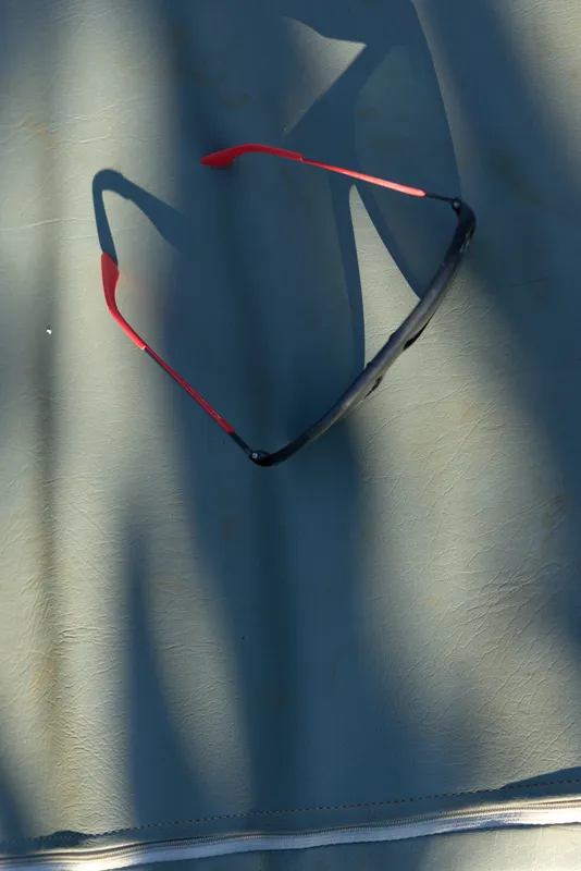 Casual lifestyle scene with sunglasses resting on soft fabric, sunlight and shadows creating a calm, minimal composition, highlighting an everyday fashion accessory for outdoor moments and sunny days